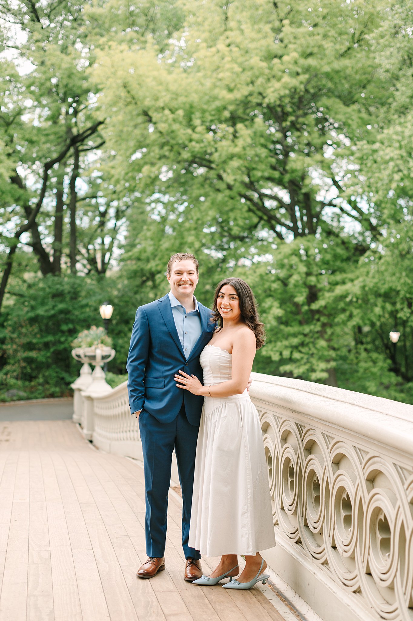 Romantic couple during a spring engagement photo shoot at Bow Bridge in Central Park.