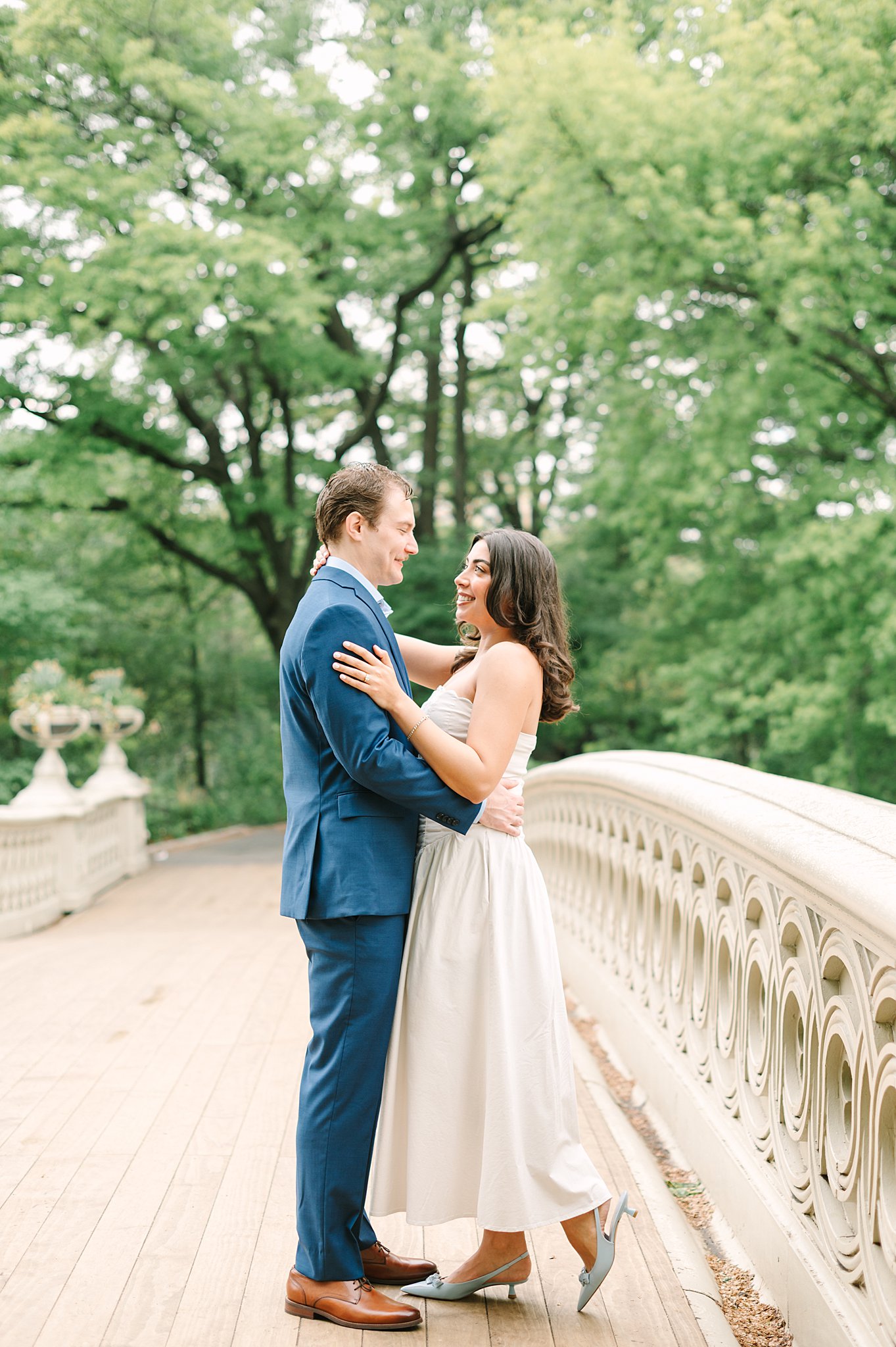 Romantic couple during a spring engagement photo shoot at Bow Bridge in Central Park.