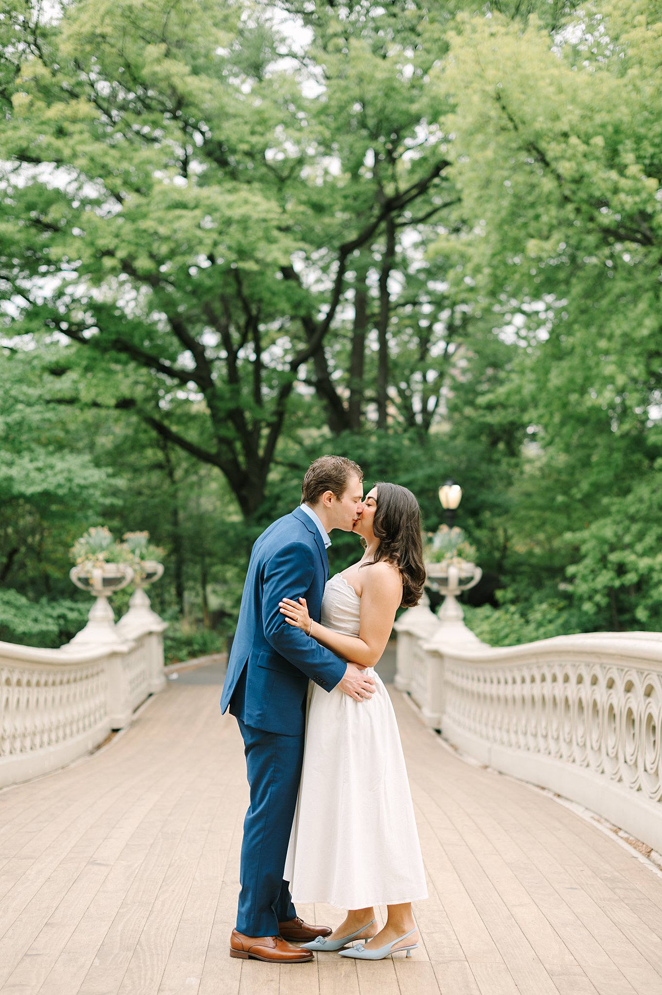 Couple walking hand-in-hand beneath cherry blossoms during a spring engagement session in Central Park NYC.