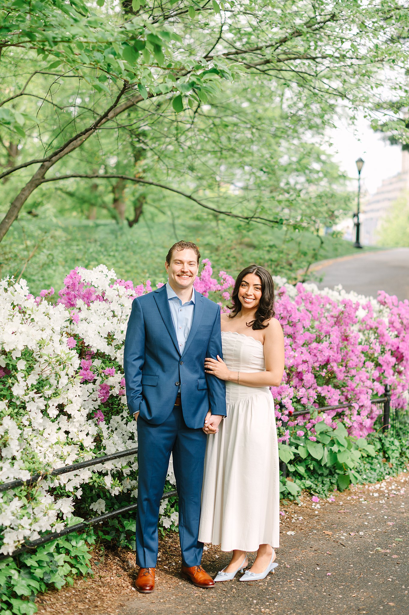Engaged couple embracing among blooming trees in Central Park during springtime