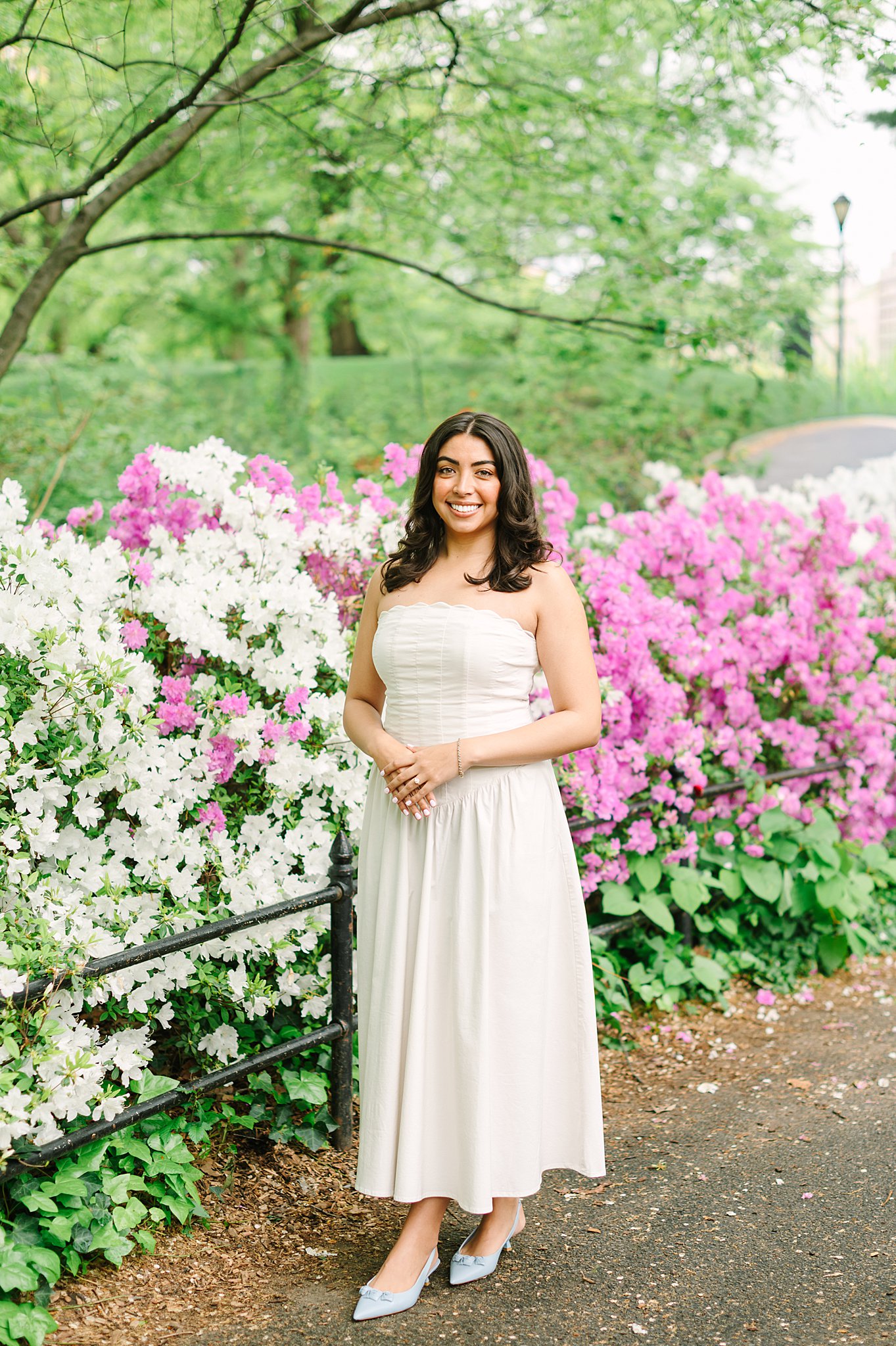 Engaged couple embracing among blooming trees in Central Park during springtime