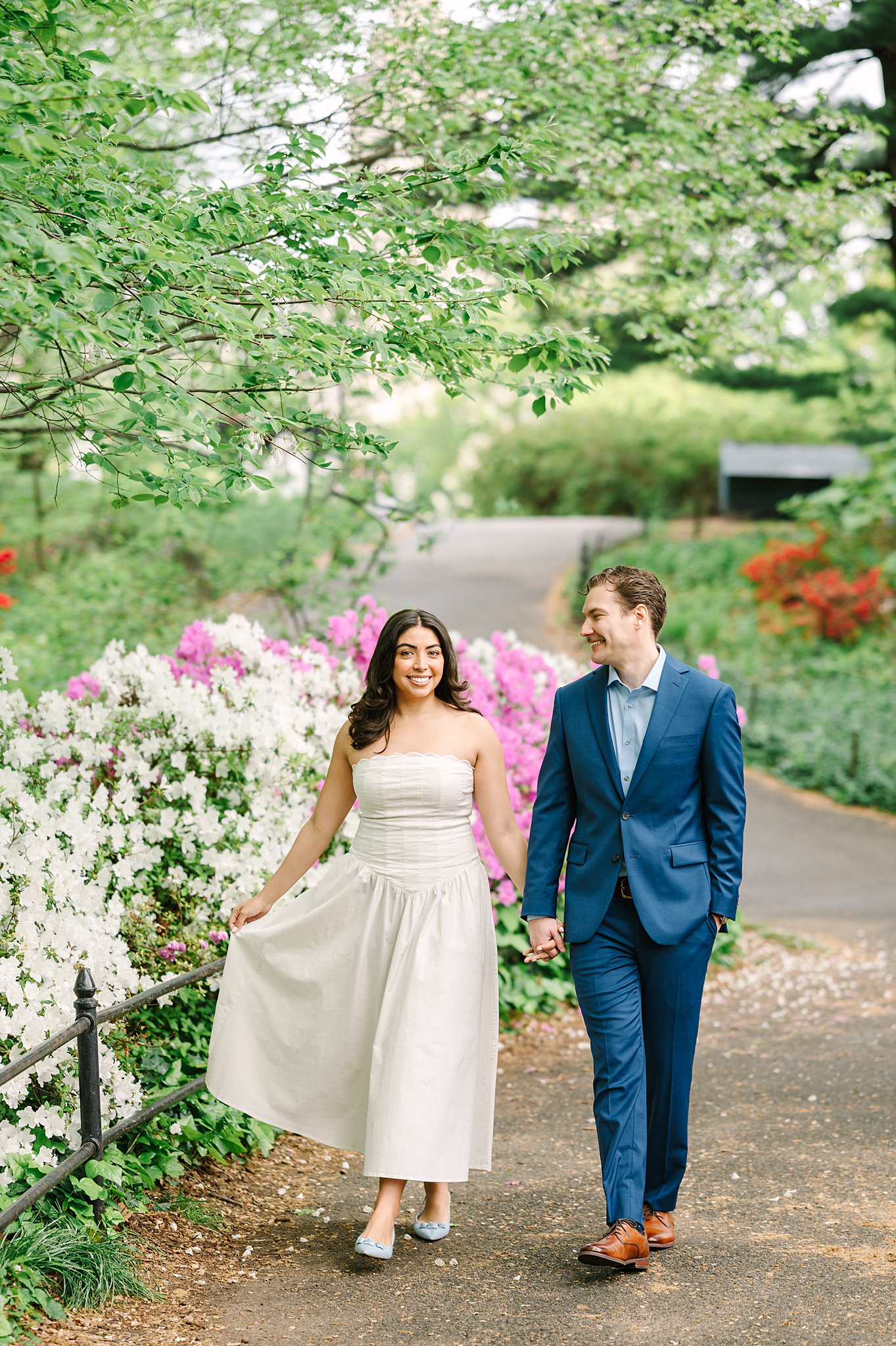 Engaged couple embracing among blooming trees in Central Park during springtime